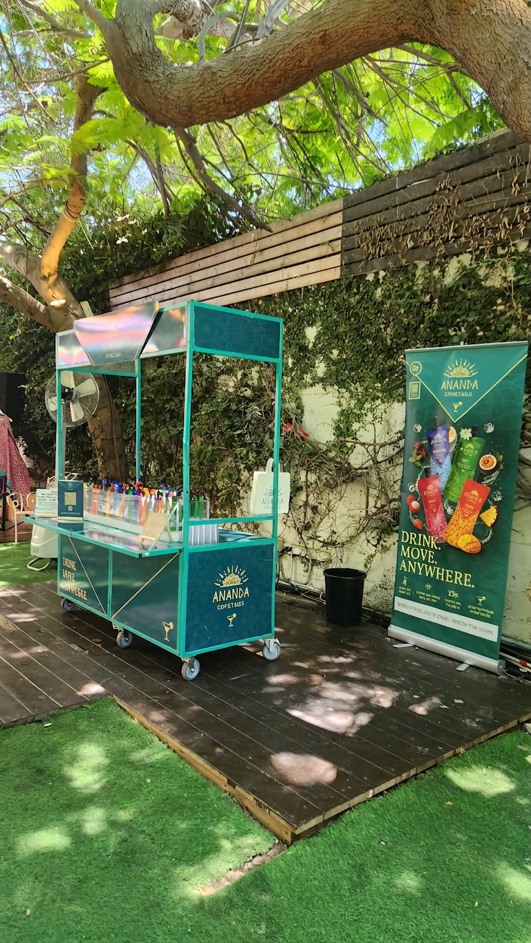 עמדת בר ממותגת של אננדה קוקטיילים בגן אירועים פתוח עם רול-אפ