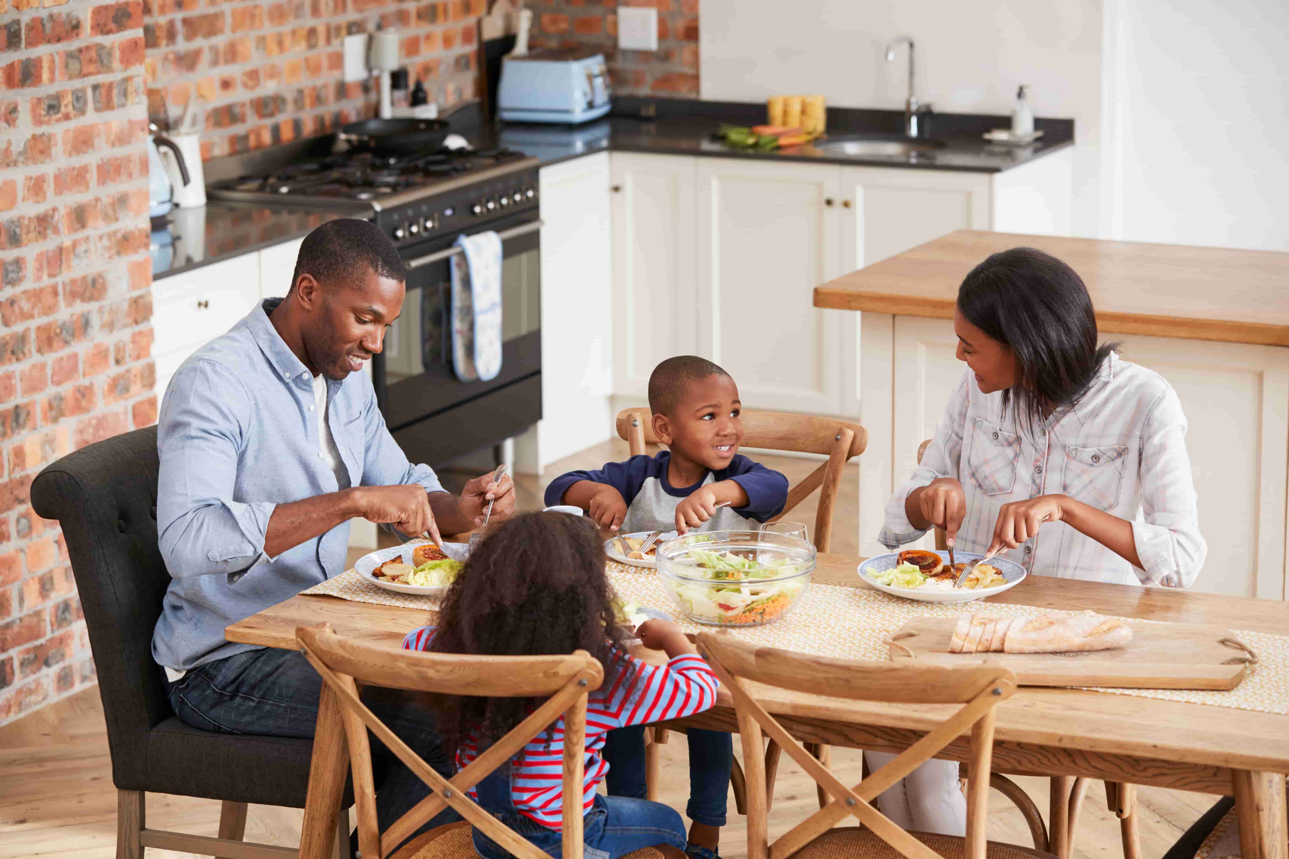 Family of four gathered around modern dining table