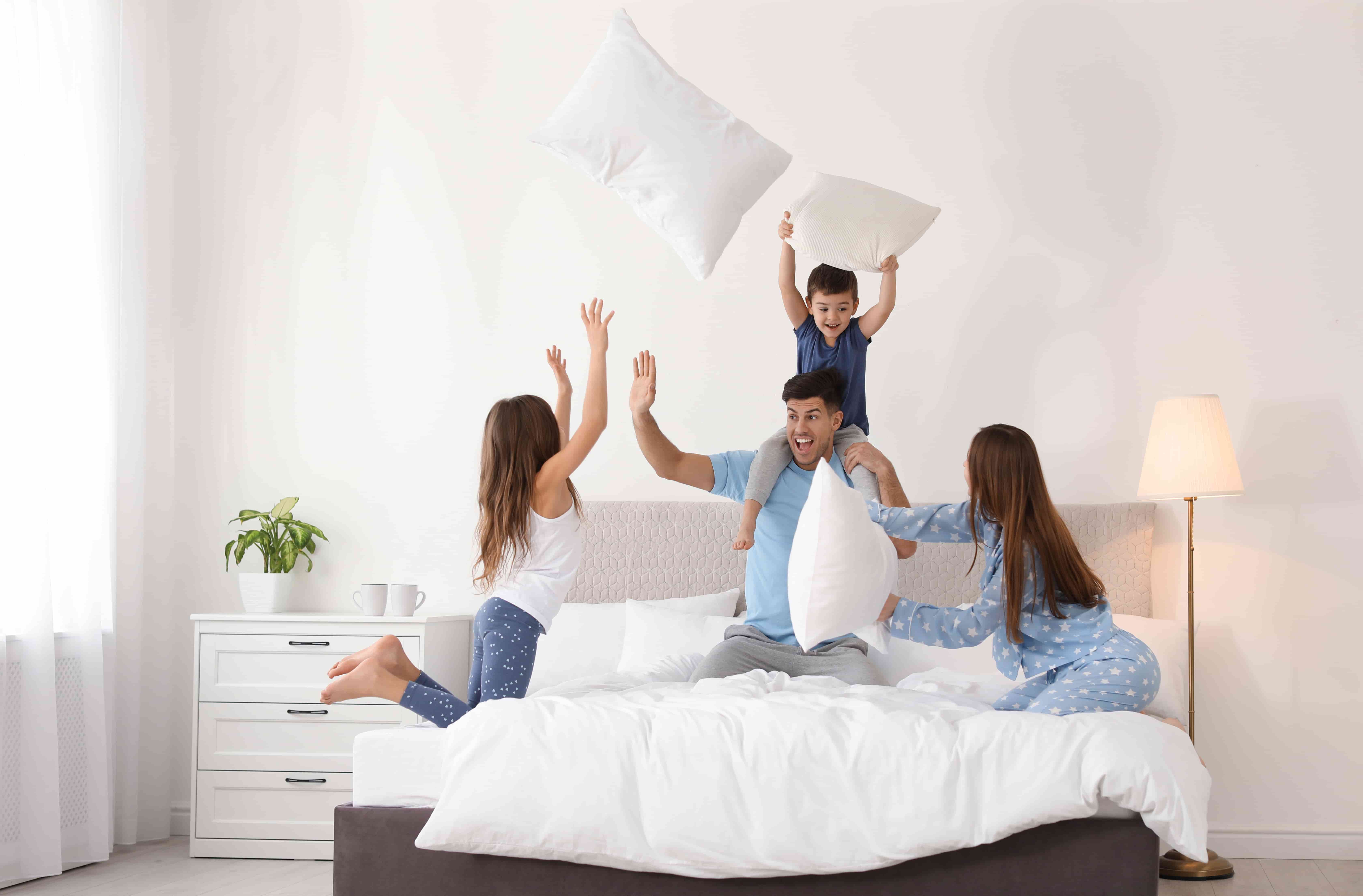Family having fun with pillows on a bed showing bedding in everyday use from Lusomé